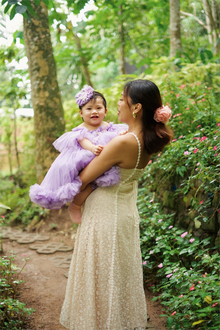 Giana in her mother's arms on a garden path