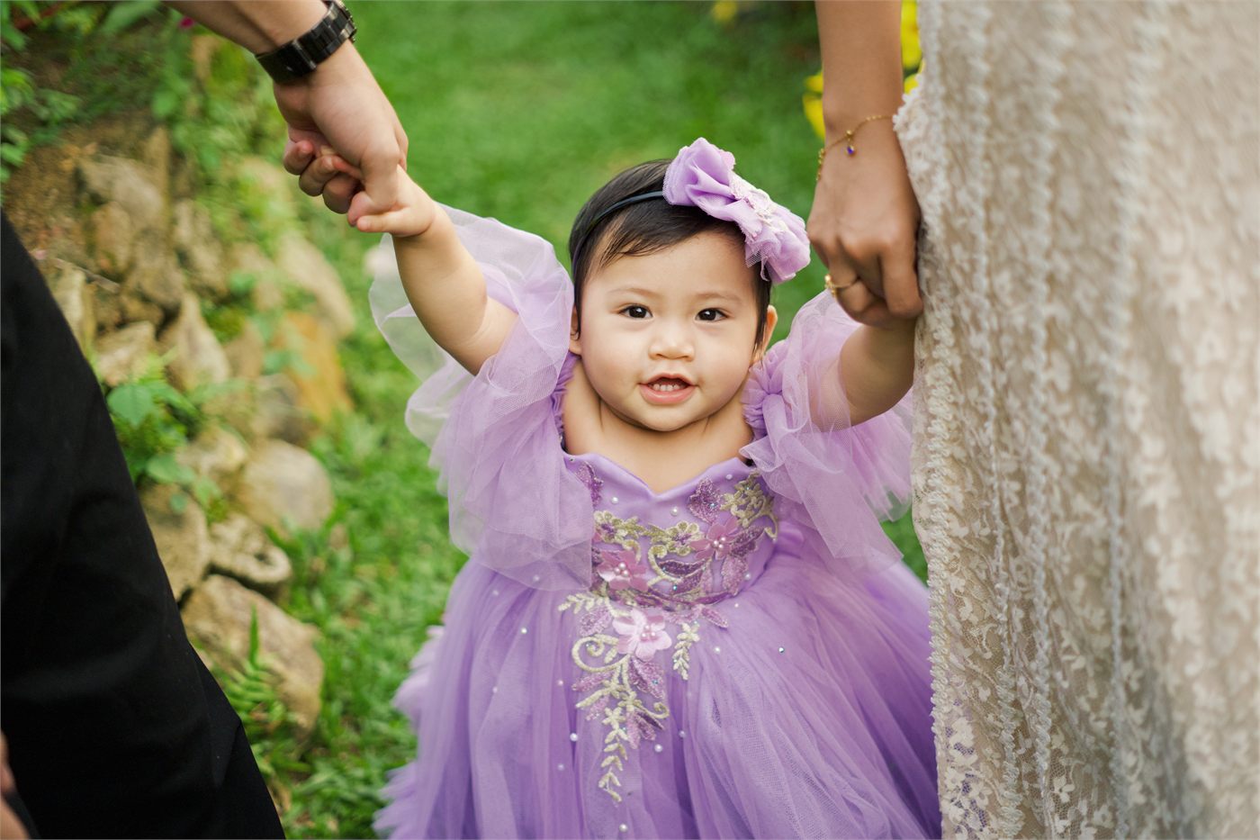 Giana walking while holding both parents' hands