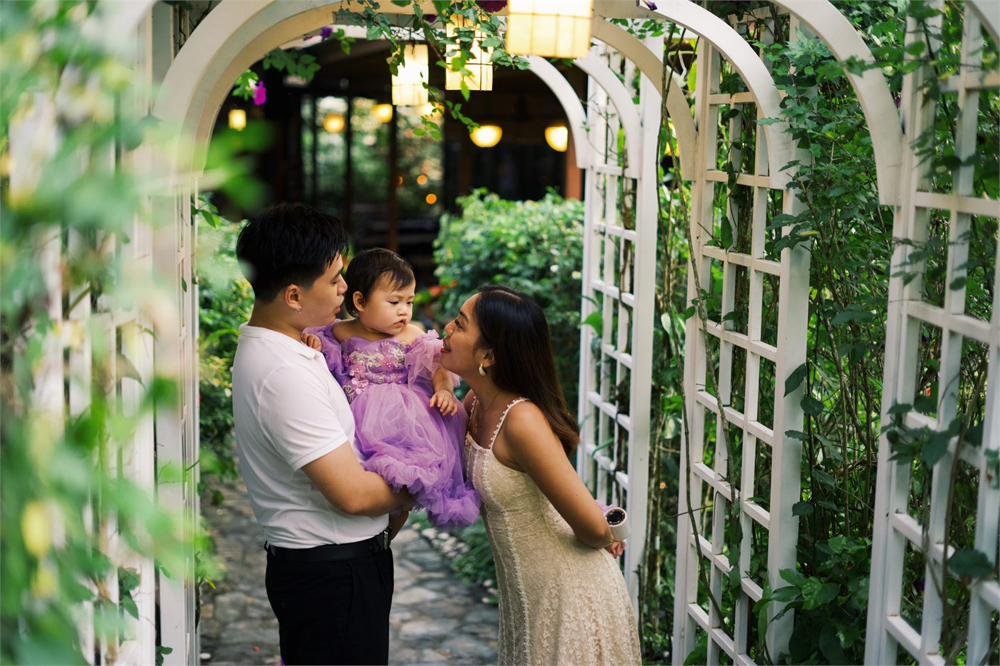 Giana with her parents beneath a garden arch